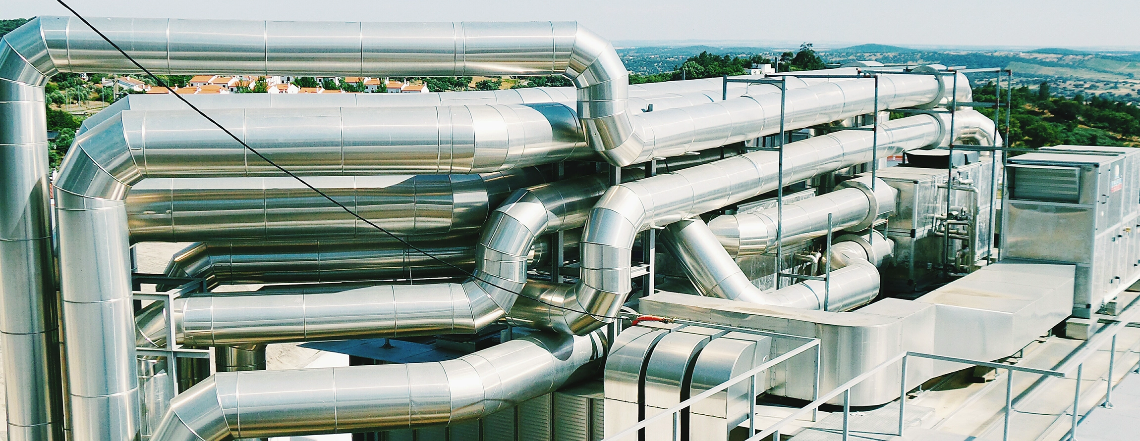 Skomplikowany system zewnętrznych rurociągów przemysłowych. Rurociągi te są zamontowane na dachu budynku.